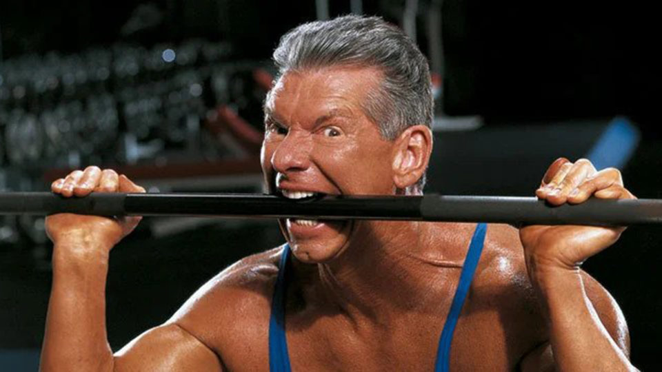 Vince McMahon biting a dumbbell during a Muscle & Fitness photo shoot